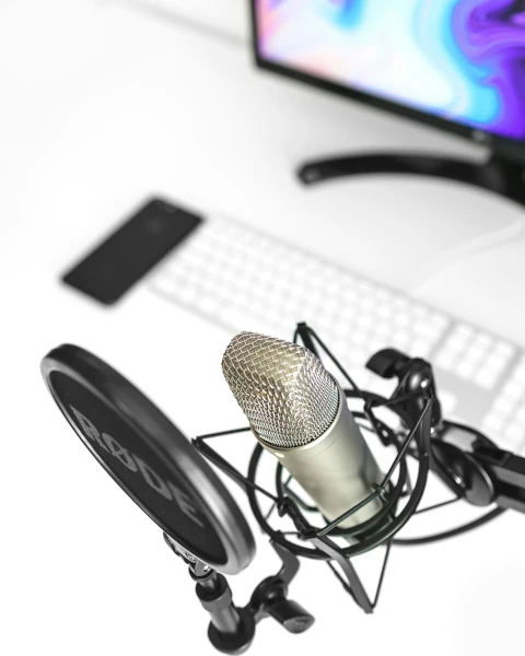 Podcast - ein Microphone mit Schutz vor einem Monitor mit Tastatur