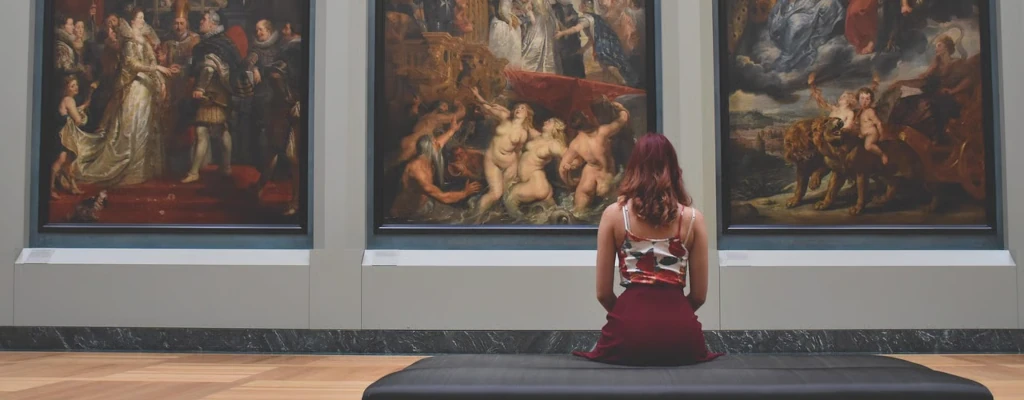 Realität - Eine Frau sitzt auf einer Bank vor Bildern